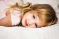 Close-up portrait of beautiful cute little 3 years old blond girl with blue eyes lying on bed in pink dress. Moment of relaxation Royalty Free Stock Photo