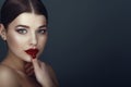 Close up portrait of beautiful dark-haired model with perfect make up and centre part sleek bun touching her ideal shaped lips Royalty Free Stock Photo