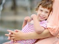 Close-up portrait of beautiful disabled girl in the arms of his mother having fun in fountain of public park at sunny summer day. Royalty Free Stock Photo