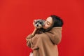 Close up portrait of a beautiful dog-owner female in a hoodie hugging her adorable york terrier in front of the  red wall Royalty Free Stock Photo