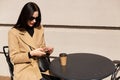 Close up portrait of beautiful elegant young woman wearing beige coat and drinking takeaway coffee while having lunch time. Pretty Royalty Free Stock Photo