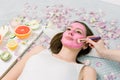 Close-up portrait of beautiful girl applying pink mud facial mask. Spa Woman applying Facial clay Mask. Beauty Royalty Free Stock Photo