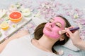 Close-up portrait of beautiful girl applying pink mud facial mask. Spa Woman applying Facial clay Mask. Beauty Royalty Free Stock Photo