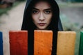 Beautiful young woman in a hood stands behind a colorful fence Royalty Free Stock Photo