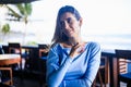 Close up portrait of beautiful girl with jewelry. Smiling Caucasian woman wearing blue dress and sitting in the beach bar. Travel Royalty Free Stock Photo