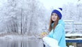 Pretty Caucasian girl dreaming looking into the distance standing outdoor with cup of tea near waterside. Royalty Free Stock Photo