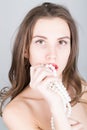 Close-up portrait of a beautiful girl with red lips, holding a pearl necklace. mouth open, pearls touches her lips. Red Royalty Free Stock Photo