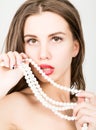 Close-up portrait of a beautiful girl with red lips, holding a pearl necklace. mouth open, pearls touches her lips. Red Royalty Free Stock Photo