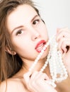 Close-up portrait of a beautiful girl with red lips, holding a pearl necklace. mouth open, pearls touches her lips. Red Royalty Free Stock Photo