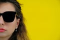 Close-up portrait of a beautiful girl on a yellow background. a woman in black glasses looks thoughtfully. human emotions Royalty Free Stock Photo