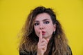 Close-up portrait beautiful girl on a yellow background. woman showing finger silence, girl showing shh sign keep secret Royalty Free Stock Photo