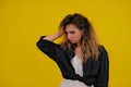 Close-up portrait of a beautiful girl on a yellow background. woman shows thoughtfulness. human emotions