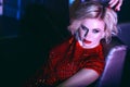 Close up portrait of beautiful glam blond model relaxing on the sofa in night club in colourful neon lights Royalty Free Stock Photo