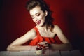 Beautiful happy young woman with creative hairstyle and colourful make up sitting at the wooden table and looking at pastry Royalty Free Stock Photo