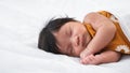 Close-up portrait of a beautiful innocent sleeping baby on white bed and blanket, multiracial newborn girl one month old sleeping