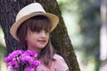 Close up portrait of a beautiful little girl with big blue eyes, with a hat while holding a bouquet of flowers Royalty Free Stock Photo