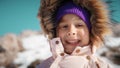 Close-up portrait of a beautiful little girl wearing warm clothes in snowy mountains in winter Royalty Free Stock Photo