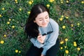 Close up portrait of beautiful millennial young woman in sunglasses sitting on meadow with yellow chamomile flowers and grass in Royalty Free Stock Photo