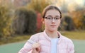 Close-up portrait of beautiful preteen girl in fashion glasses with serious face expression outside in autumn park