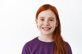 Close up portrait of beautiful red haired girl with freckles, smiling with teeth and looking happy at camera, positive Royalty Free Stock Photo