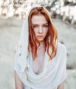 Close up portrait of a beautiful red haired girl in white medieval dress on glowing sun. Fairy tale story about brave heart woman