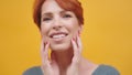 Close up portrait of a beautiful red haired middle aged woman with make up isolated on orange background Royalty Free Stock Photo