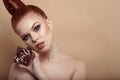 Close up portrait of beautiful red-haired woman with perfect make-up and hair scraped back into a high bun holding compact powder Royalty Free Stock Photo