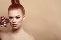 Close up portrait of beautiful red-haired woman with perfect make-up and hair scraped back into a high bun holding compact powder