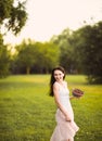 Portrait of a beautiful romantic brunette girl with a basket of cherries in a green garden