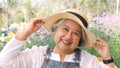 Close-up Portrait of a beautiful senior woman goes on vacation at the flower garden. Happy woman in a white straw hat resting in a Royalty Free Stock Photo