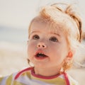 Close up portrait of beautiful small baby, blond little girl in colourful pullover at the beach outdoors Royalty Free Stock Photo