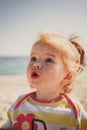 Close up portrait of beautiful small baby, blond little girl in colourful pullover at the beach outdoors. Royalty Free Stock Photo