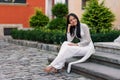 Close up portrait of beautiful asian girl dressed in Ao Dai white dress sitting on the stairs in courtyard. Royalty Free Stock Photo