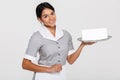 Close-up portrait of beautiful smiling woman in gray uniform holding metal tray with empty sign card, looking at camera Royalty Free Stock Photo