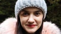 Close up portrait of beautiful smiling woman with red lipstick in knitted gray hat and jacket with pink natural fur collar Royalty Free Stock Photo