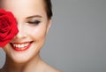 Close-up portrait of beautiful smiling woman with red rose. Royalty Free Stock Photo