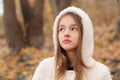 Close-up portrait of beautiful thoughtful dreaming little girl in white hoody coat staying in autumn forest Royalty Free Stock Photo