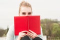 Close-up portrait of beautiful woman hiding behind red book Royalty Free Stock Photo