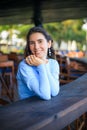Close up portrait of beautiful woman with jewelry. Smiling Caucasian woman wearing blue dress and sitting in the beach bar. Travel Royalty Free Stock Photo