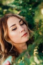 Close up portrait of a beautiful woman posing at camera with a coniferous tree. Vertical Royalty Free Stock Photo