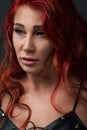 Close-up portrait of a beautiful woman with red long curly hair against black background. concept of skin care. professional make Royalty Free Stock Photo