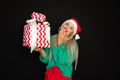 Portrait of beautiful woman in santa hat with toothy happy face, black background, copy space, studio shot, weared in green red Royalty Free Stock Photo