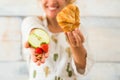 Close up and portrait of beautiful woman showing at the camera healthy food like fruit and in the other hand bad alimentation like