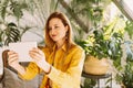 Close-up portrait beautiful woman sitting at garden while holding digital tablet. Young attractive happy woman is using tablet Royalty Free Stock Photo