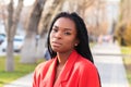 Close up portrait of a beautiful young african american woman with pigtails in a red business suit smiling and walking along the Royalty Free Stock Photo