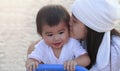 Close up portrait beautiful young asian mother kissing her little baby in park. Happy lovely mother kiss her little daughter. Royalty Free Stock Photo