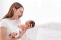Close up portrait of beautiful young asian mother with newborn baby. Side view of a young woman playing with her little baby in Royalty Free Stock Photo
