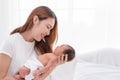 Close up portrait of beautiful young asian mother with newborn baby. Side view of a young woman playing with her little baby in Royalty Free Stock Photo