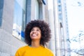 Close up portrait of beautiful young black woman smiling outdoors in the street of a grey city - businesswoman walking and having Royalty Free Stock Photo