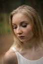 Close up portrait - Beautiful young blonde woman forest nymph in white dress in evergreen wood Royalty Free Stock Photo